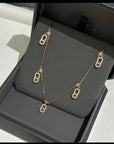 Gold chain necklace with crystal-studded oval pendants displayed in a black jewelry box.