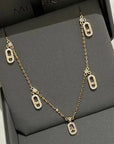 Gold chain necklace with crystal-studded oval pendants displayed in a black jewelry box.