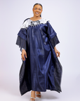 A woman wearing a metallic navy blue kaftan gown with an embroidered white floral neckline and wide sleeves, styled for special occasions.