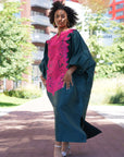 Model wearing luxurious teal Boubou dress with bold pink embroidery and voluminous sleeves.