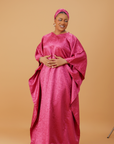 Woman wearing a radiant magenta kaftan with wide sleeves and a matching head wrap, styled for special occasions.