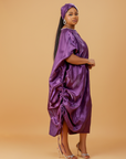 Woman wearing a regal purple satin kaftan with side drawstring detail and matching head wrap.