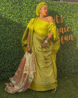 Elegant woman in a gold Show Stopper Boubou with draped detailing, posing gracefully at an outdoor event.