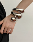 Three-layered metallic cuff bracelets in polished gold and silver finishes.