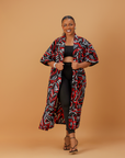 Woman wearing a bold red, black, and white abstract print kimono over a black crop top and leggings.
