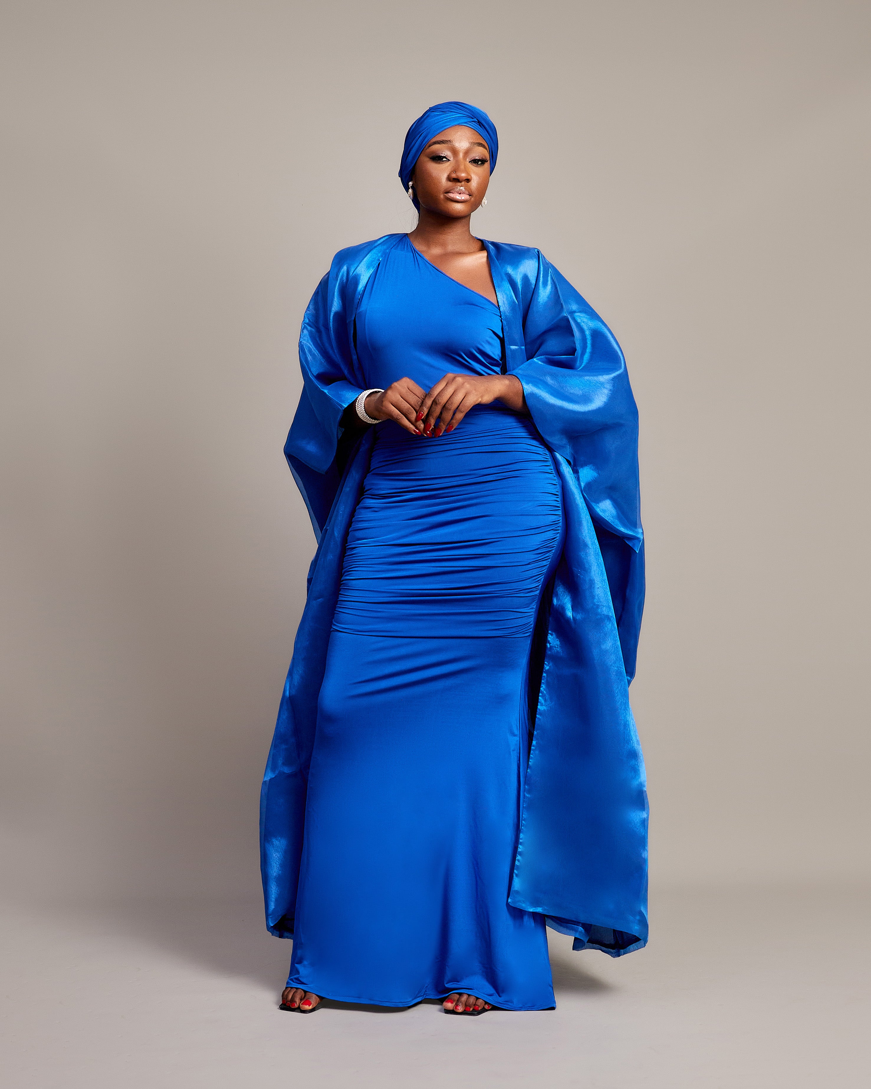 Woman wearing the Buubu Signature Set in royal blue, featuring a ruched floor-length gown, kimono overlay, and matching headwrap.
