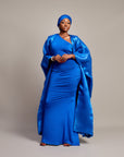 Woman wearing the Buubu Signature Set in royal blue, featuring a ruched floor-length gown, kimono overlay, and matching headwrap.

