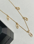 Gold chain necklace with crystal-studded oval pendants displayed in a black jewelry box.
