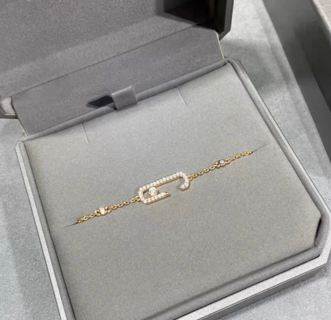 Gold chain necklace with crystal-studded oval pendants displayed in a black jewelry box.
