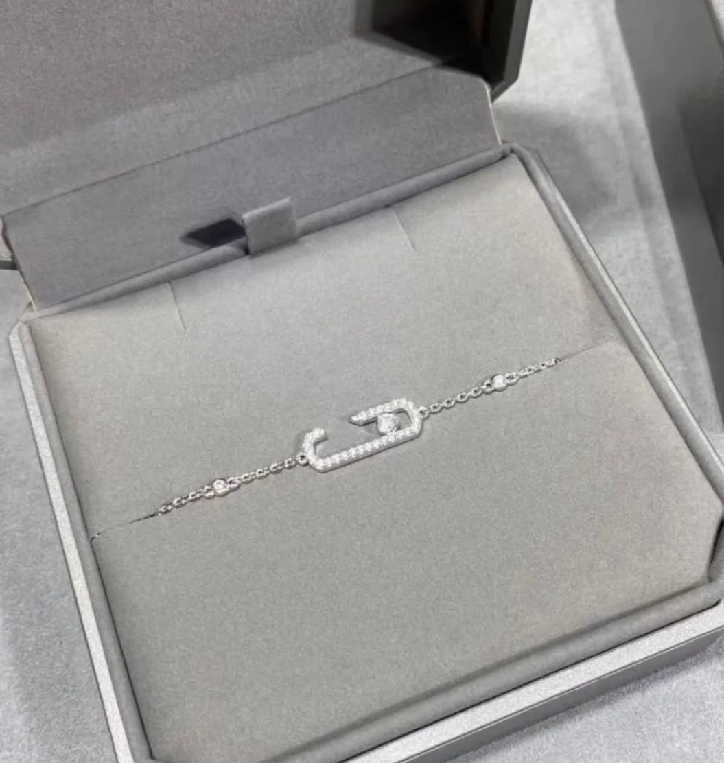 silver  chain necklace with crystal-studded oval pendants displayed in a black jewelry box.
