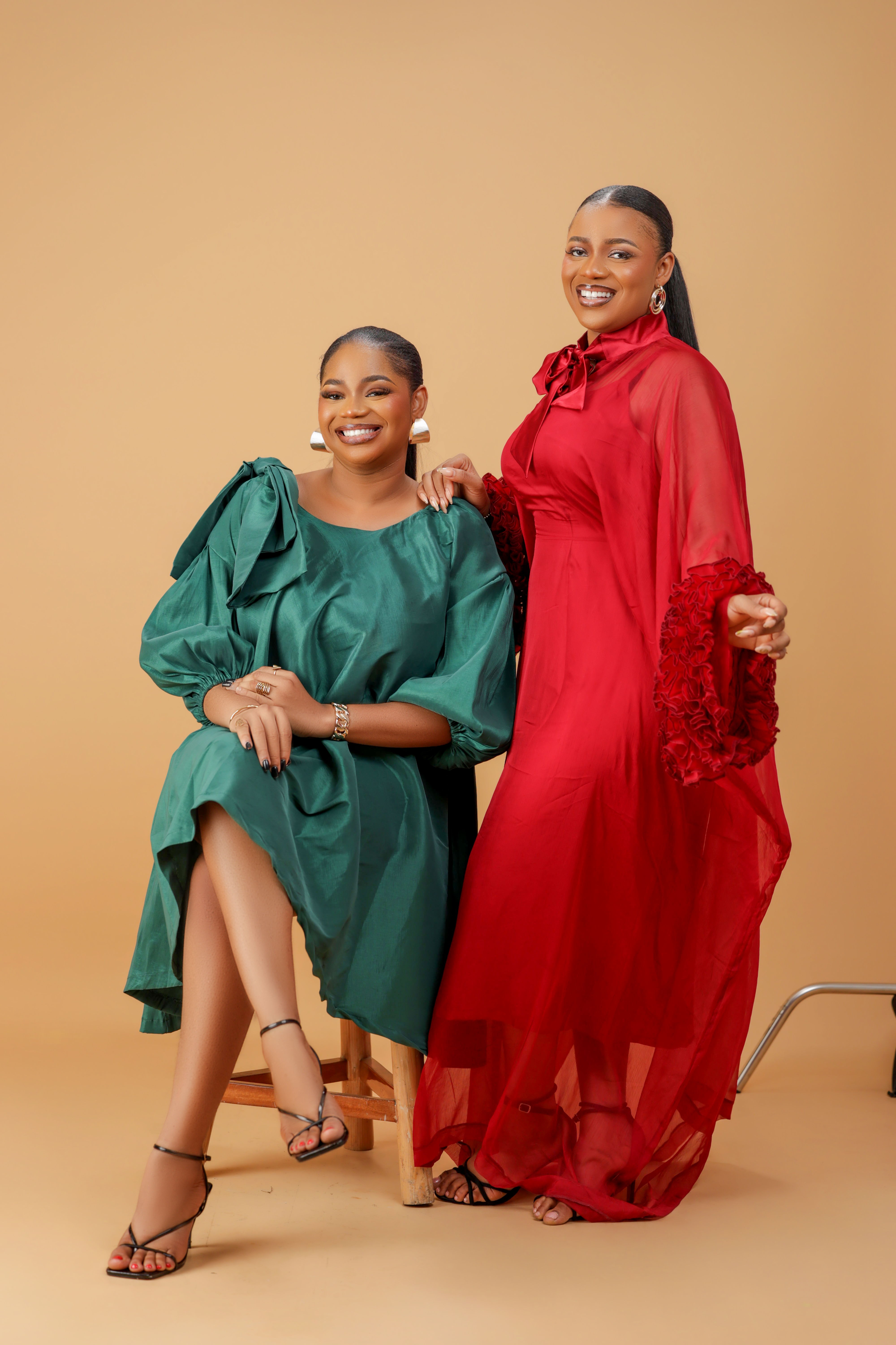Model wearing an emerald green satin bow sleeve dress with voluminous sleeves and structured bow detail on the shoulder.
