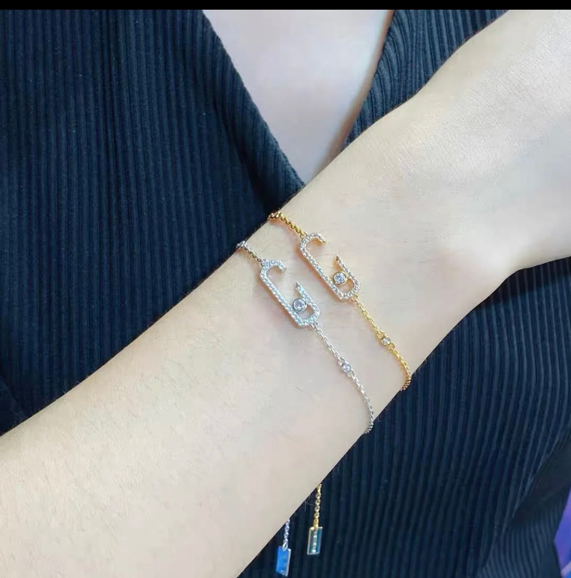 Gold chain necklace with crystal-studded oval pendants displayed in a black jewelry box.
