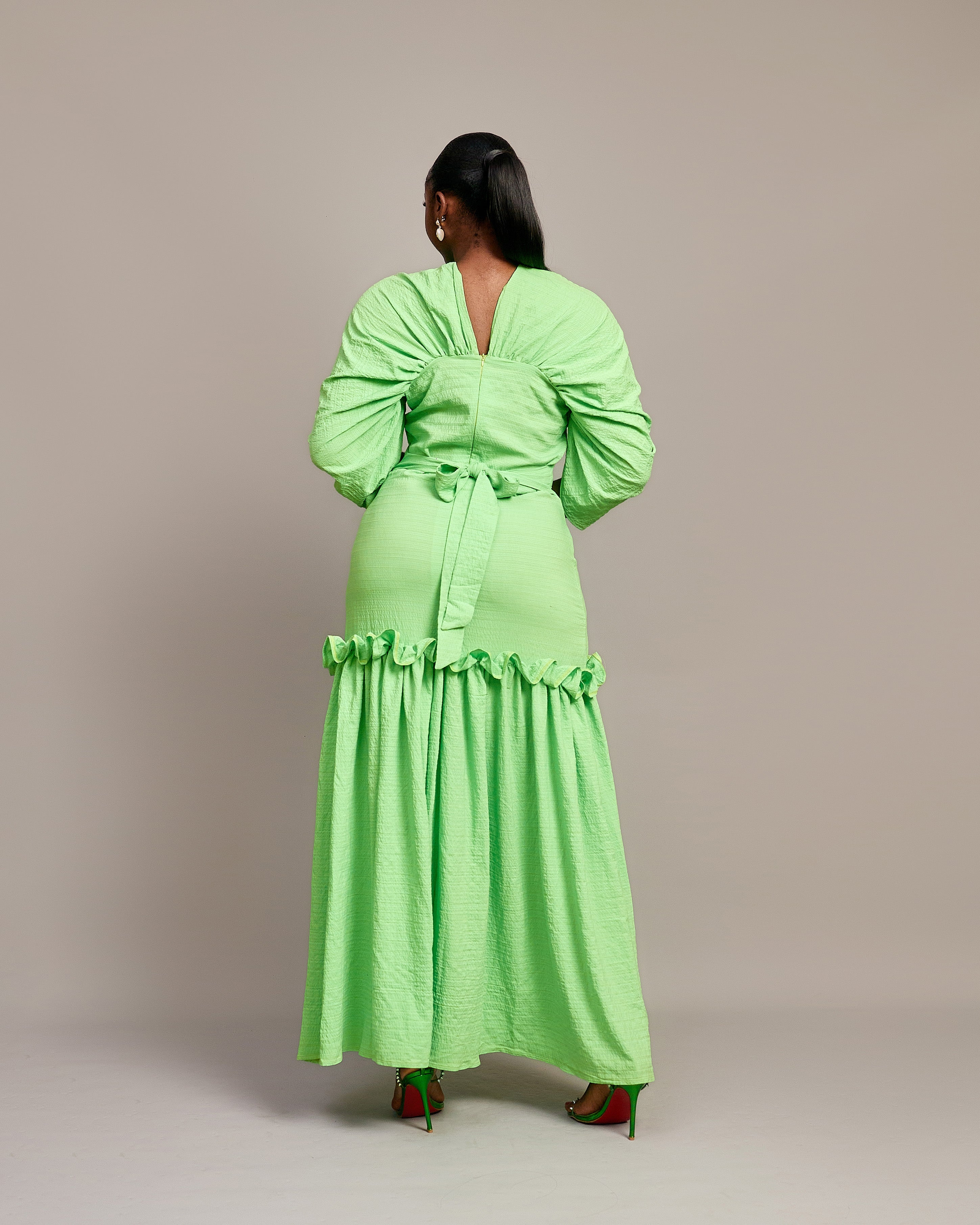 A lady wearing the Ine maxi dress featuring a draped V neckline, gathered waist detailing, and ruched hem accents.
