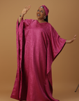 Woman wearing a radiant magenta kaftan with wide sleeves and a matching head wrap, styled for special occasions.
