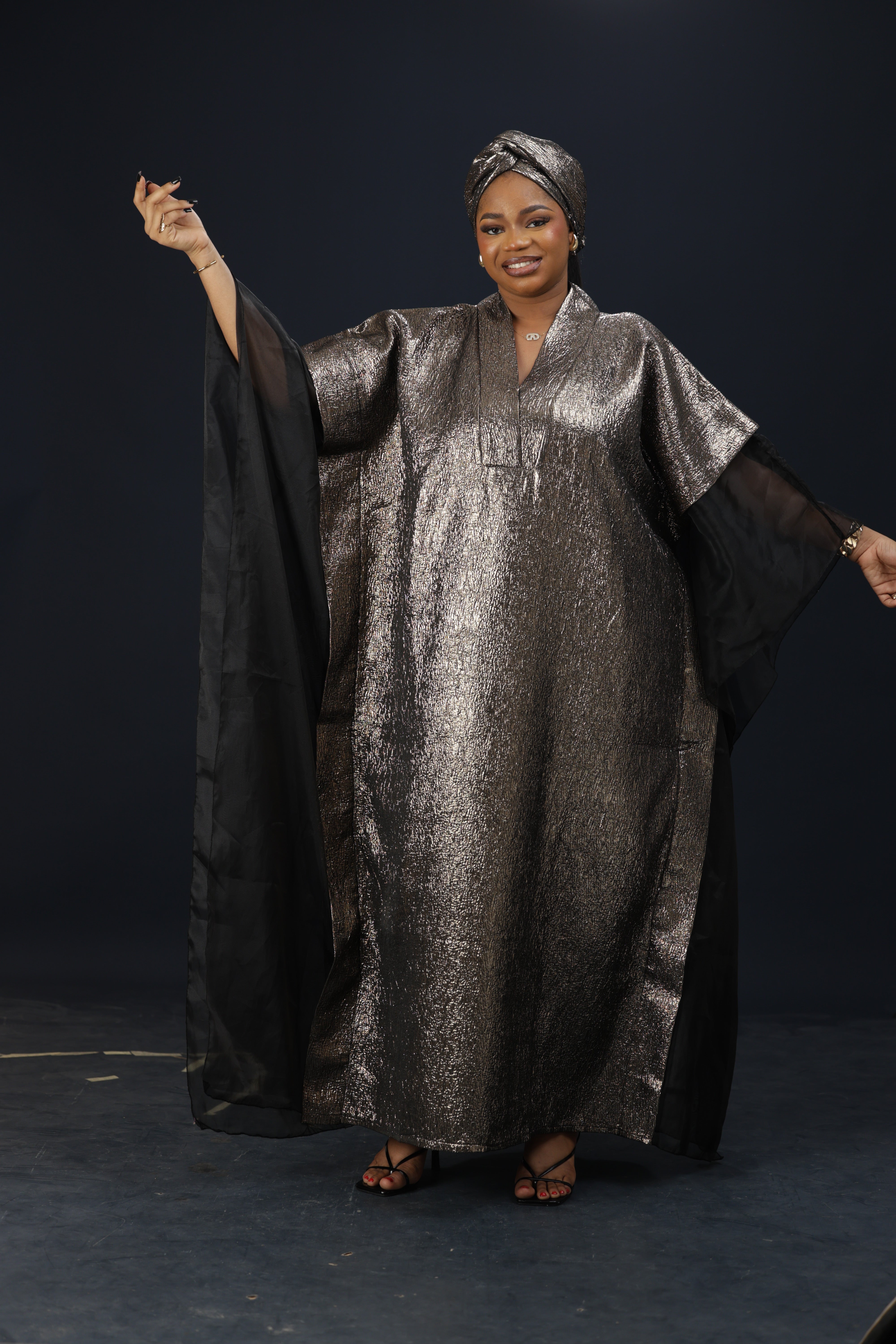Model wearing the Royal Essence metallic kaftan dress with flowing sleeves and elegant shimmer finish.

