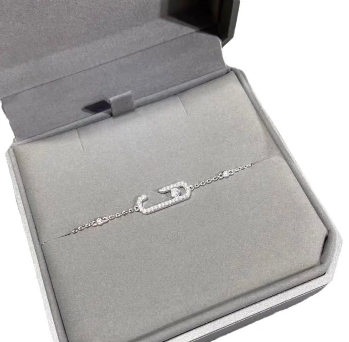 Silver  chain necklace with crystal-studded oval pendants displayed in a black jewelry box.
