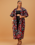 Woman wearing a bold red, black, and white abstract print kimono over a black crop top and leggings.
