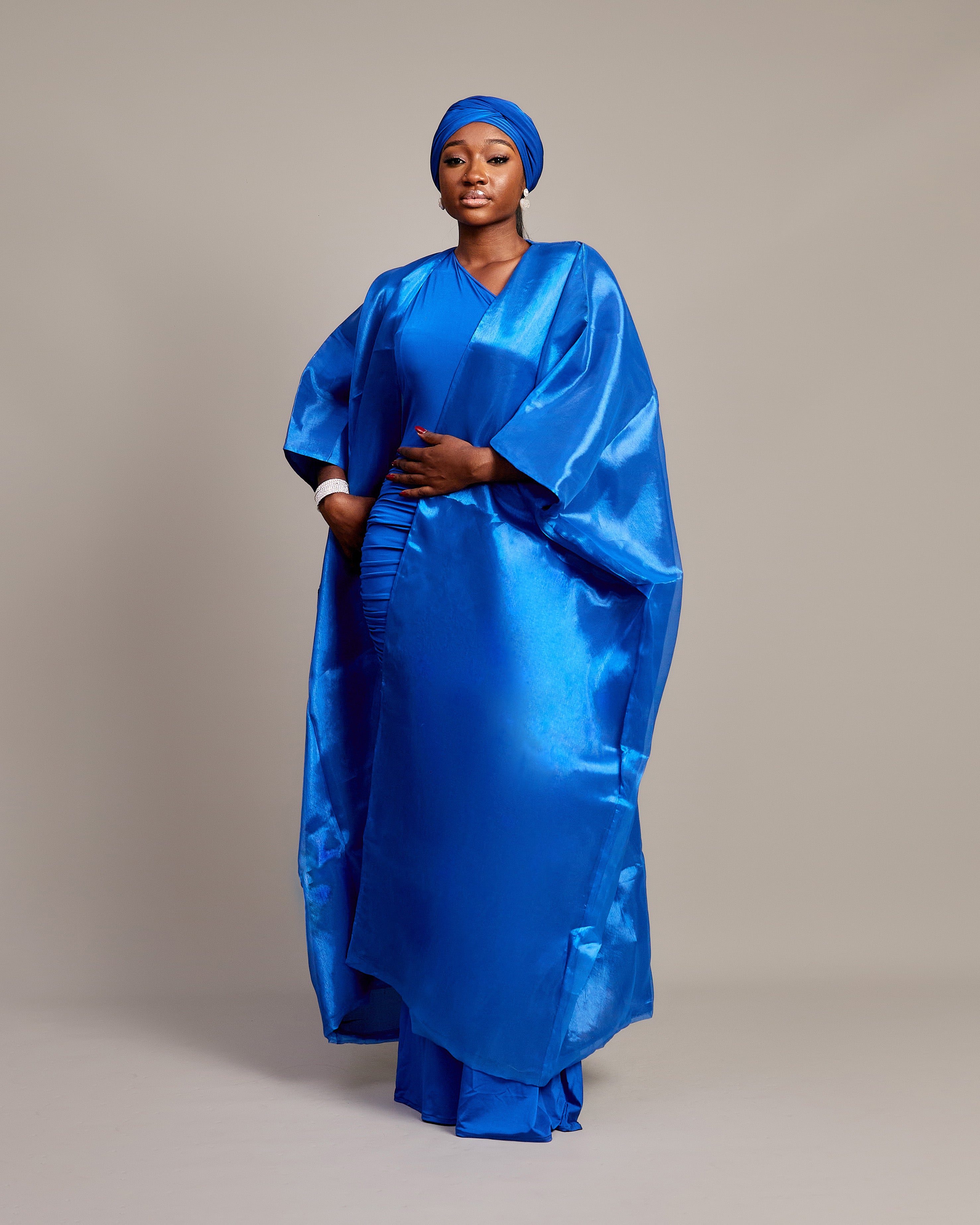 Woman wearing the Buubu Signature Set in royal blue, featuring a ruched floor-length gown, kimono overlay, and matching headwrap.
