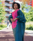 Model wearing luxurious teal Boubou dress with bold pink embroidery and voluminous sleeves.
