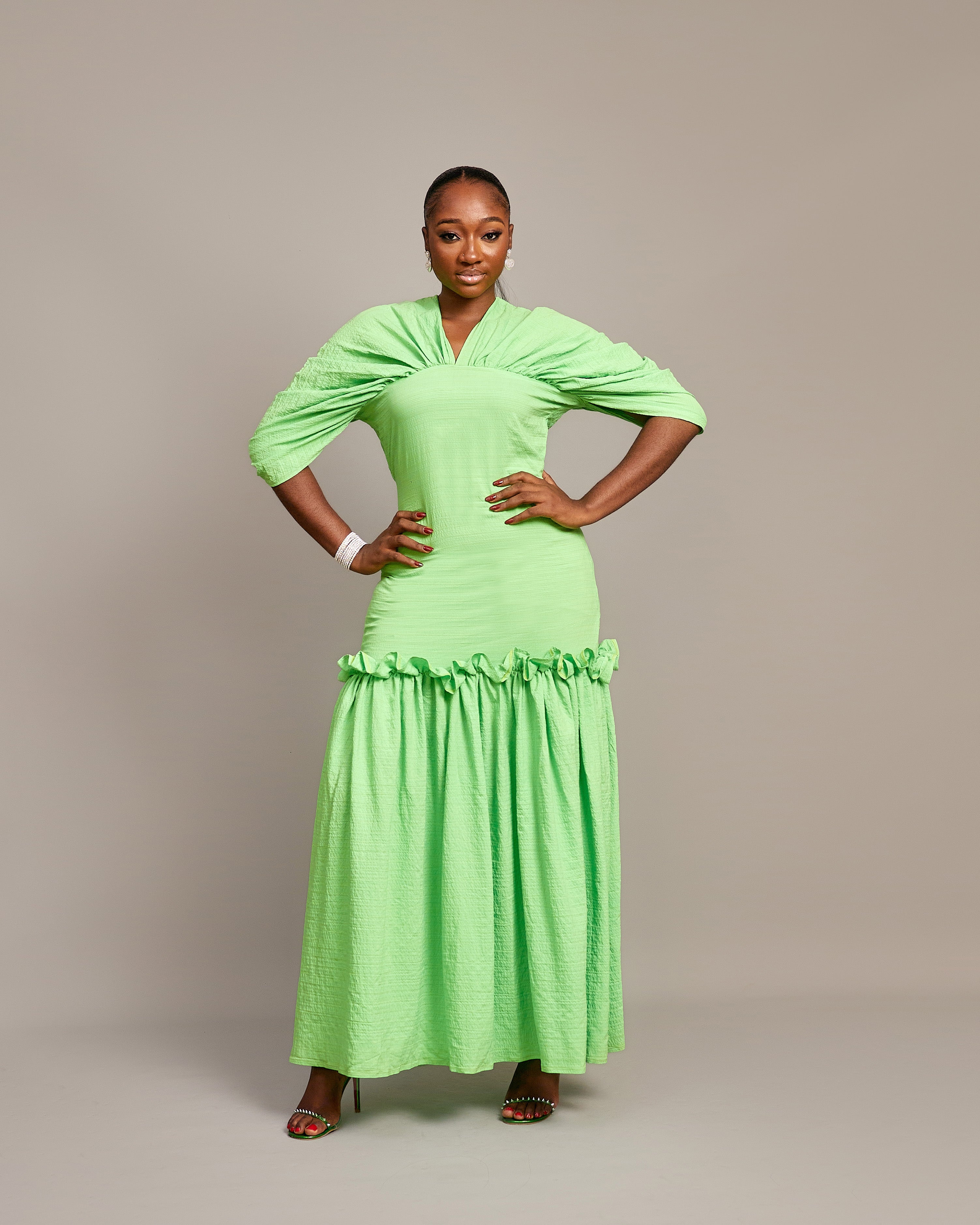 A lady wearing the Ine maxi dress  featuring a draped V neckline, gathered waist detailing, and ruched hem accents.
