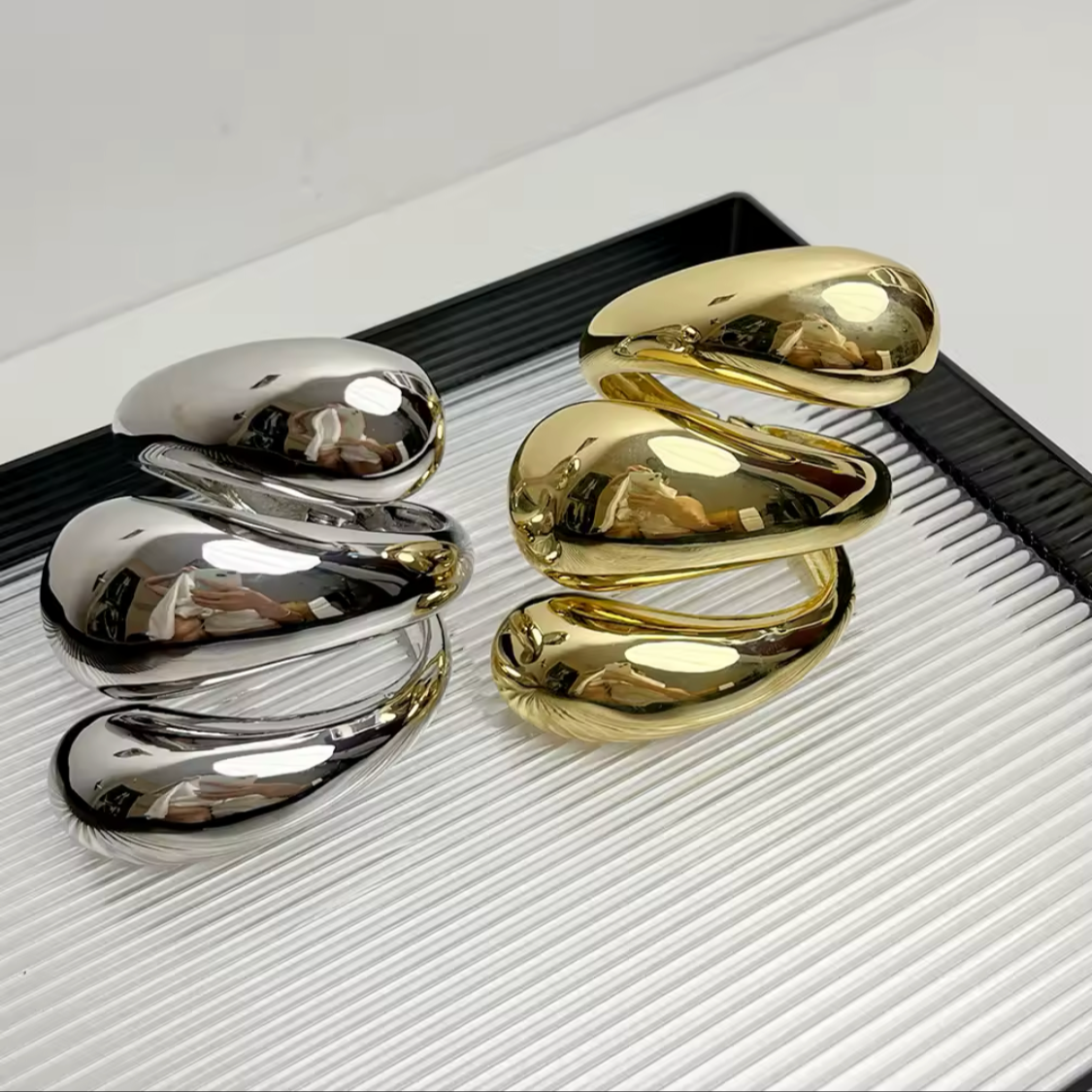 Three-layered metallic cuff bracelets in polished gold and silver finishes.
