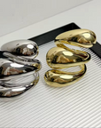 Three-layered metallic cuff bracelets in polished gold and silver finishes.