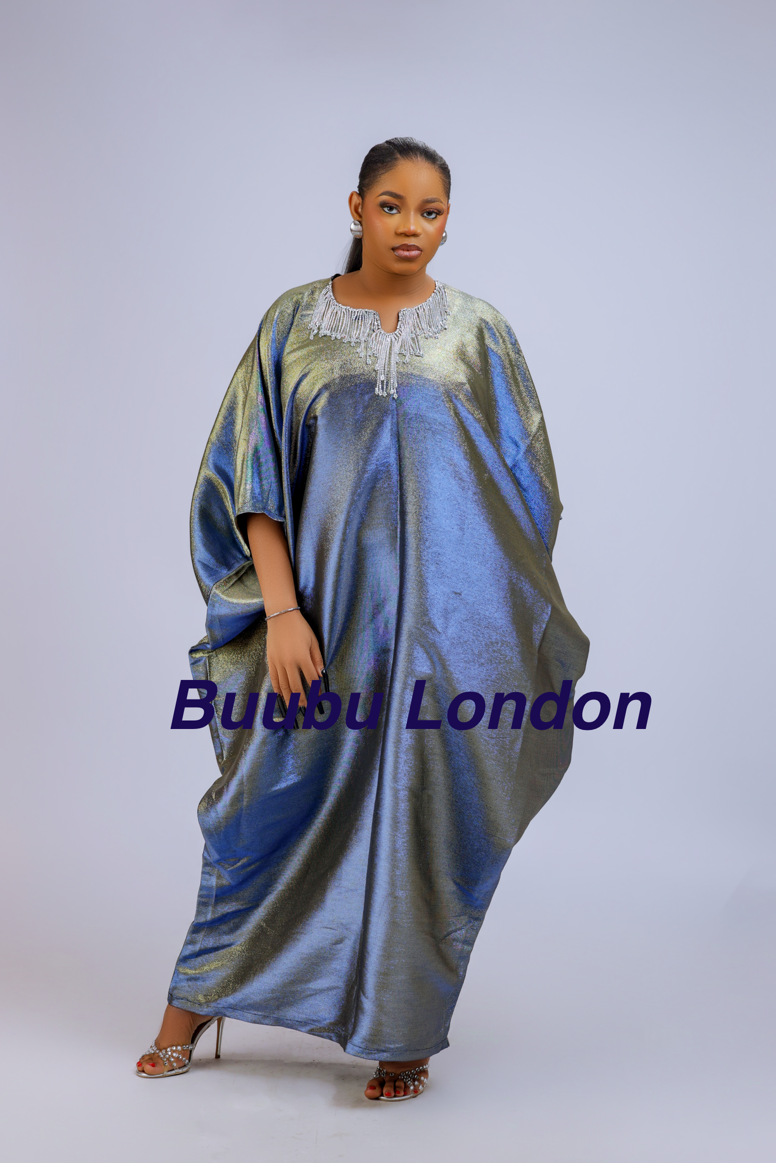 Woman wearing a shiny metallic blue-green cupped chain dress with loose sleeves and embellished neckline.
