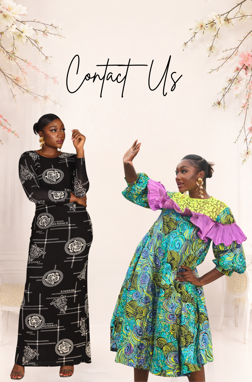 Two women modeling African wax print dresses in a styled indoor setting with floral branches at the top and the text 'Contact Us' written in script. The woman on the left wears a long black dress with white geometric and circular patterns.