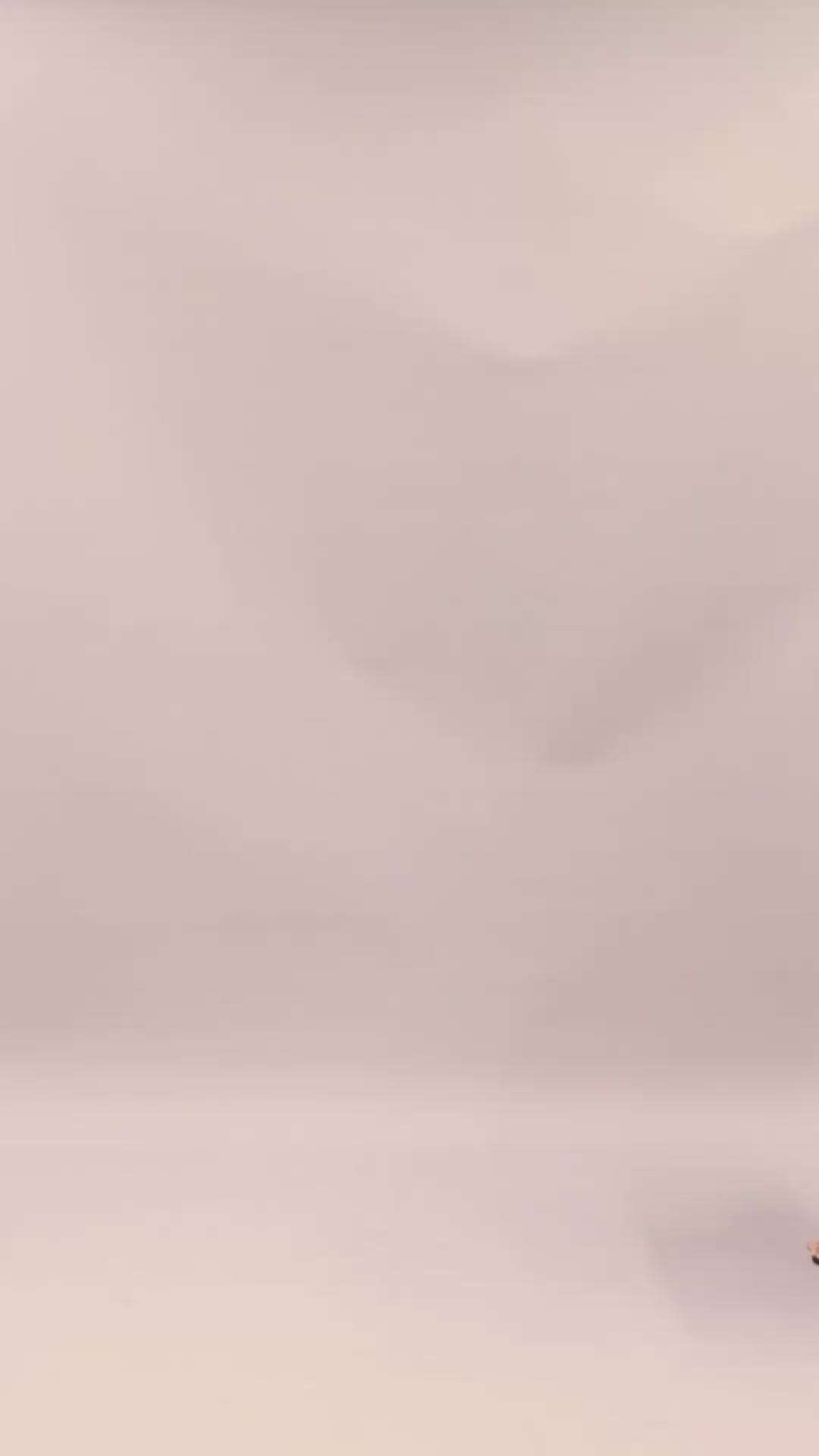 woman wearing the Tella Dress in navy. Maxi gowns with ruffle sides, long sleeves, and bow-tie neckline.
