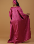 Woman wearing a radiant magenta kaftan with wide sleeves and a matching head wrap, styled for special occasions.
